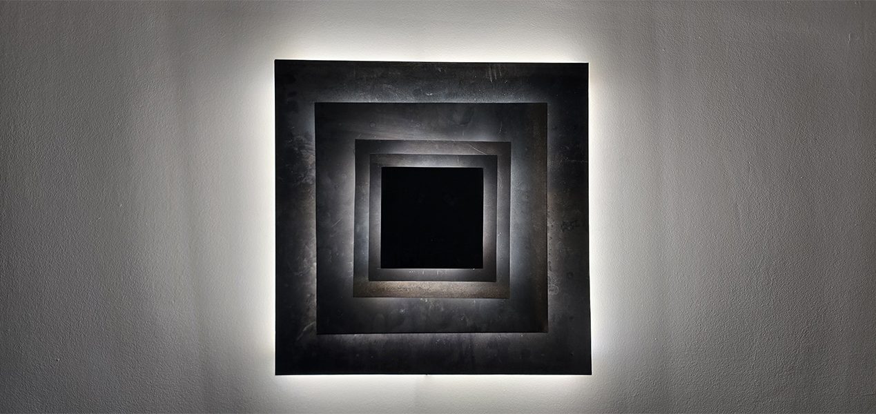 Sculpture lumineuse murale Sype 010, jeu de carrés d’acier et de lumière créant une profondeur hypnotique.