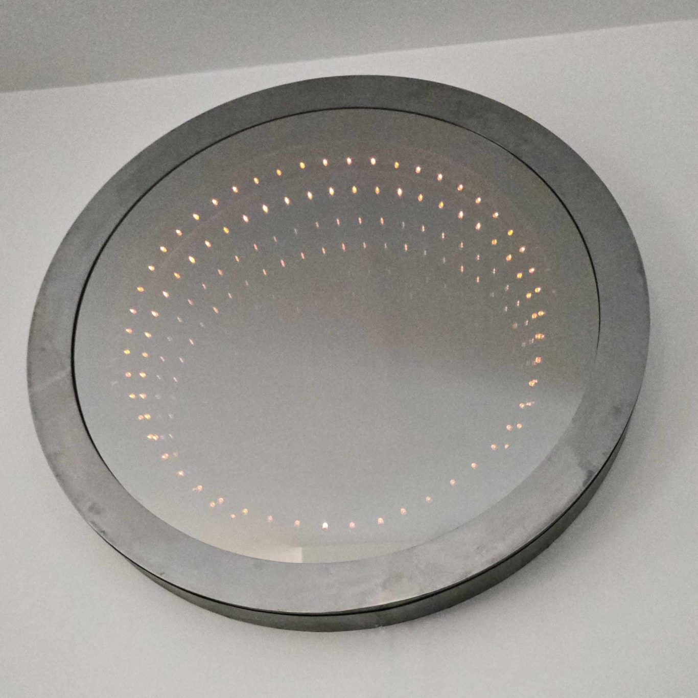 Détail du Miroir infini rond Sype 013, structure en acier brut et verre poli, cercle de LED intégré.