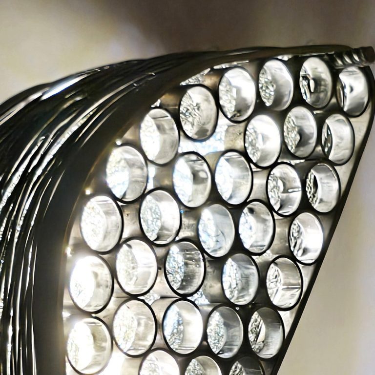 Regards sur la lumière – Dialogue entre acier brut et éclat lumineux. Détail d’une sculpture lumineuse en acier poli par Sype Design – reflets métalliques et diffusion de la lumière.