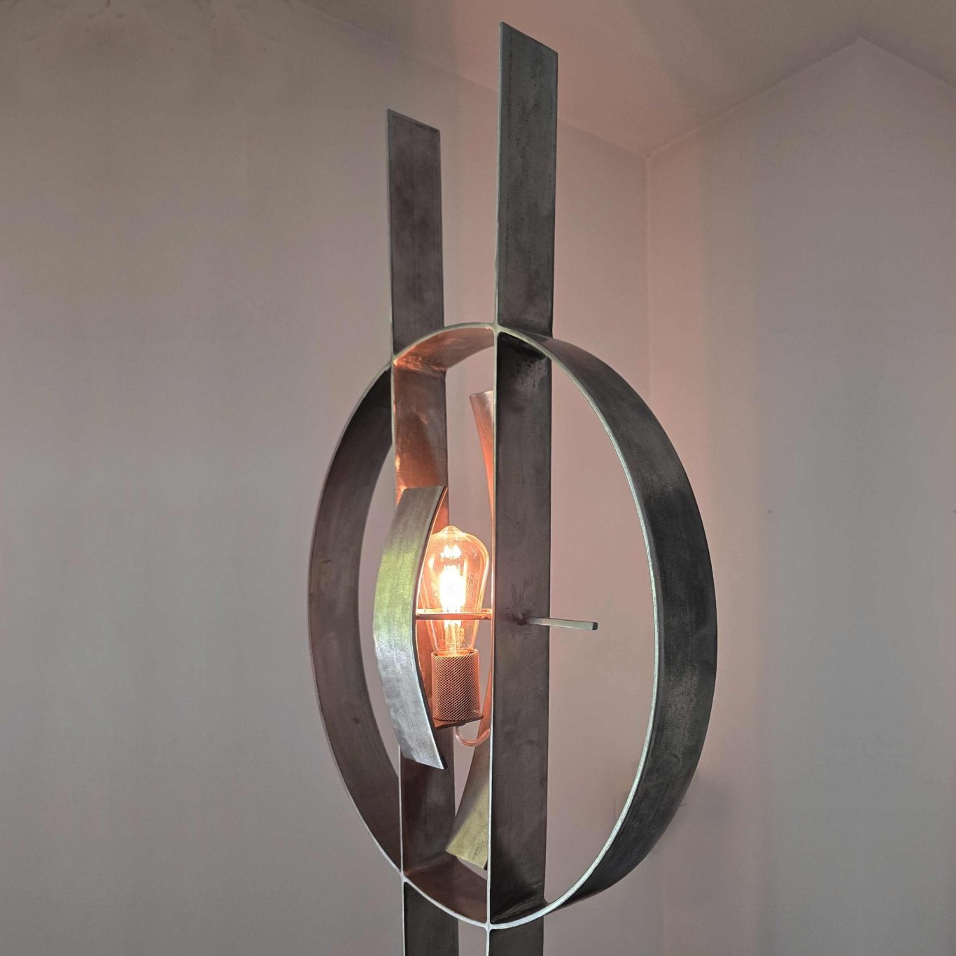 Détail de la lampe Sype 008 Le Temps Suspendu, anneau en acier et ampoule centrale évoquant la précision horlogère.