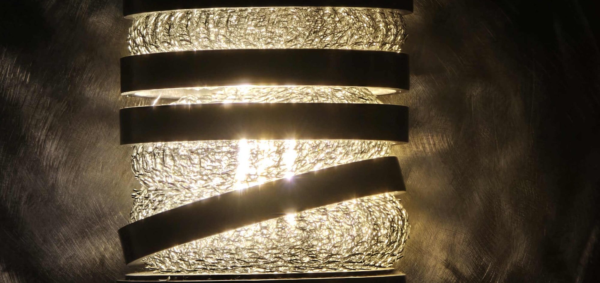 Détail de la lampe Spirale d’acier Sype 006, structure hélicoïdale en acier brut et tressage lumineux.