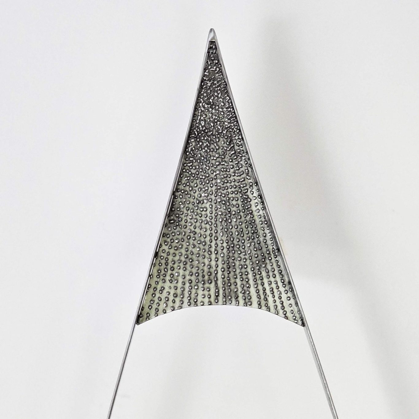 Détail supérieur de l’œil lumineux Sype 018, pointe en acier texturé révélant le travail artisanal du métal.