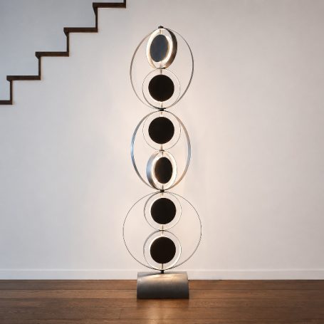 Sype 021 – Orbites silencieuses, lampadaire sculpture en acier brut Sype 021, sculpture lumineuse en acier brut composée d'anneaux circulaires orientables diffusant une lumière indirecte.