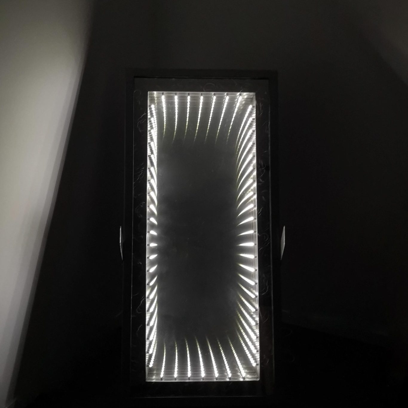 Sculpture lumineuse Sype 002, miroir infini en acier brut éclairé en perspective.