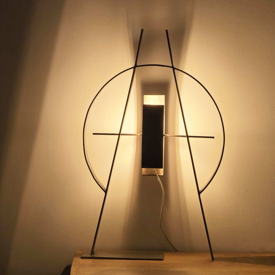 Le Compas Sype 009, sculpture lumineuse en acier brut projetant des lignes de lumière géométriques.