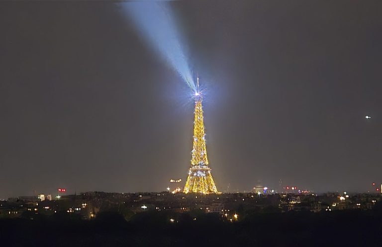 Eiffel Tower and Architectural Lighting Eiffel Tower illuminated at night with a powerful beam of light rising into the dark sky.