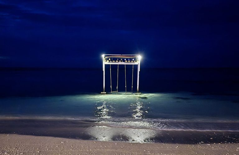 Light Installation on a Beach at Night Illuminated installation on a beach at night, creating a contrast between artificial light and the surrounding darkness.