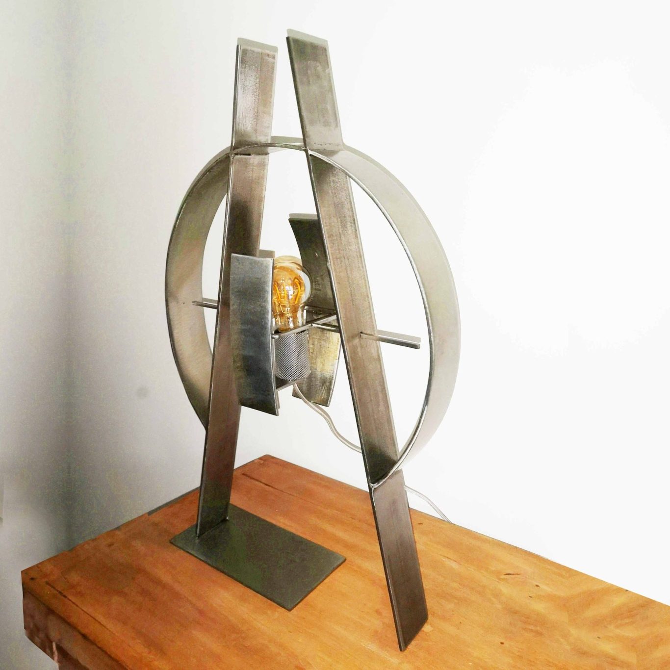 Structure de la lampe Sype 009 Le Compas, acier brut et cercle parfait évoquant la précision du compas.